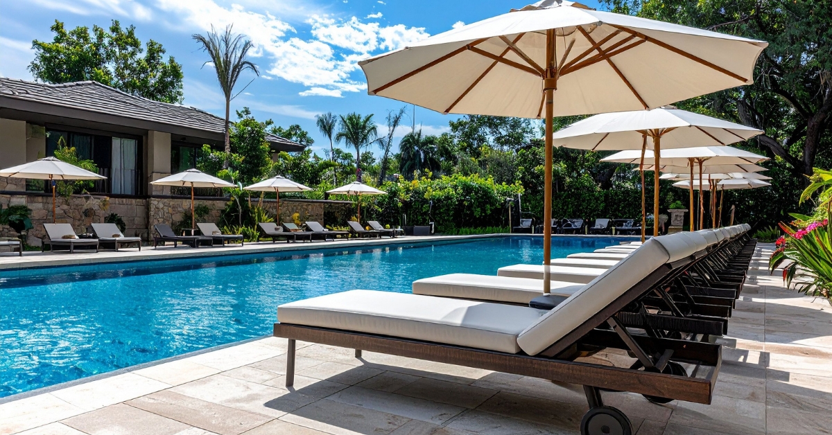 Imagem de cadeiras de praia com sombra em frente a uma piscina